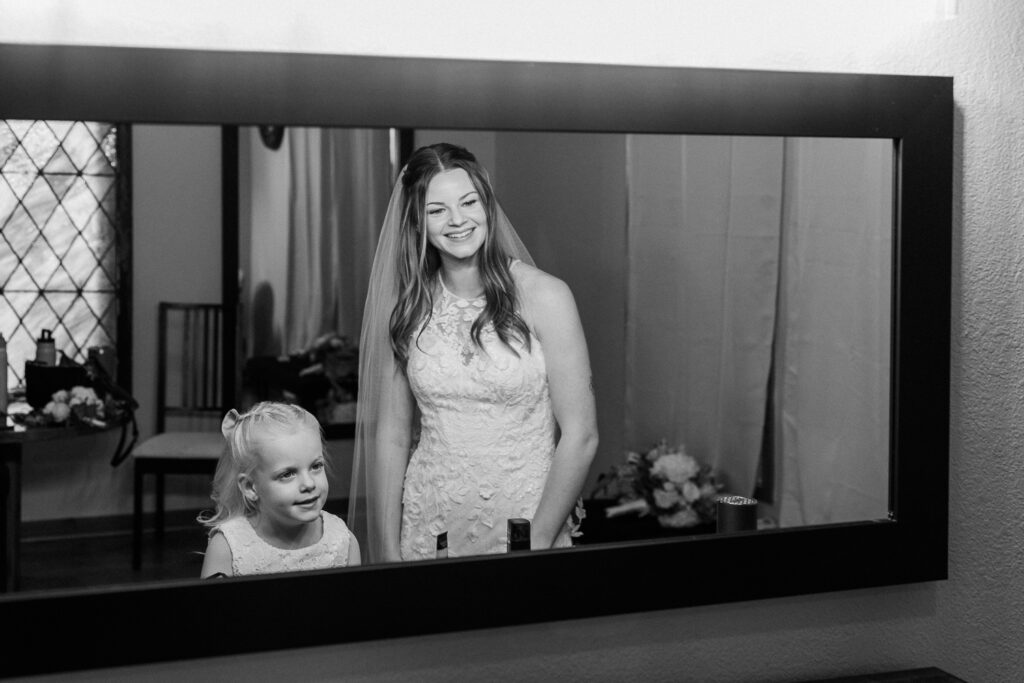 Bride with daughter smiling in the mirror at one another in the getting ready bridal suite at Serendipity venue in Flagstaff. 