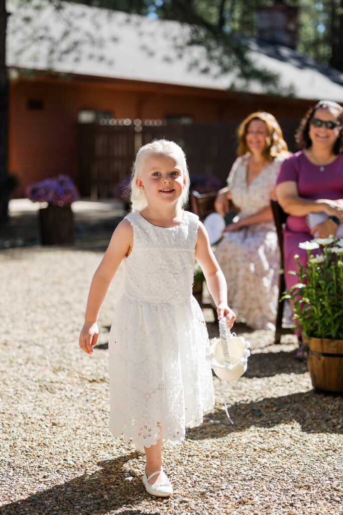 Flower girl walking down aisle at the ceremony site at Serendipity venue in Flagstaff