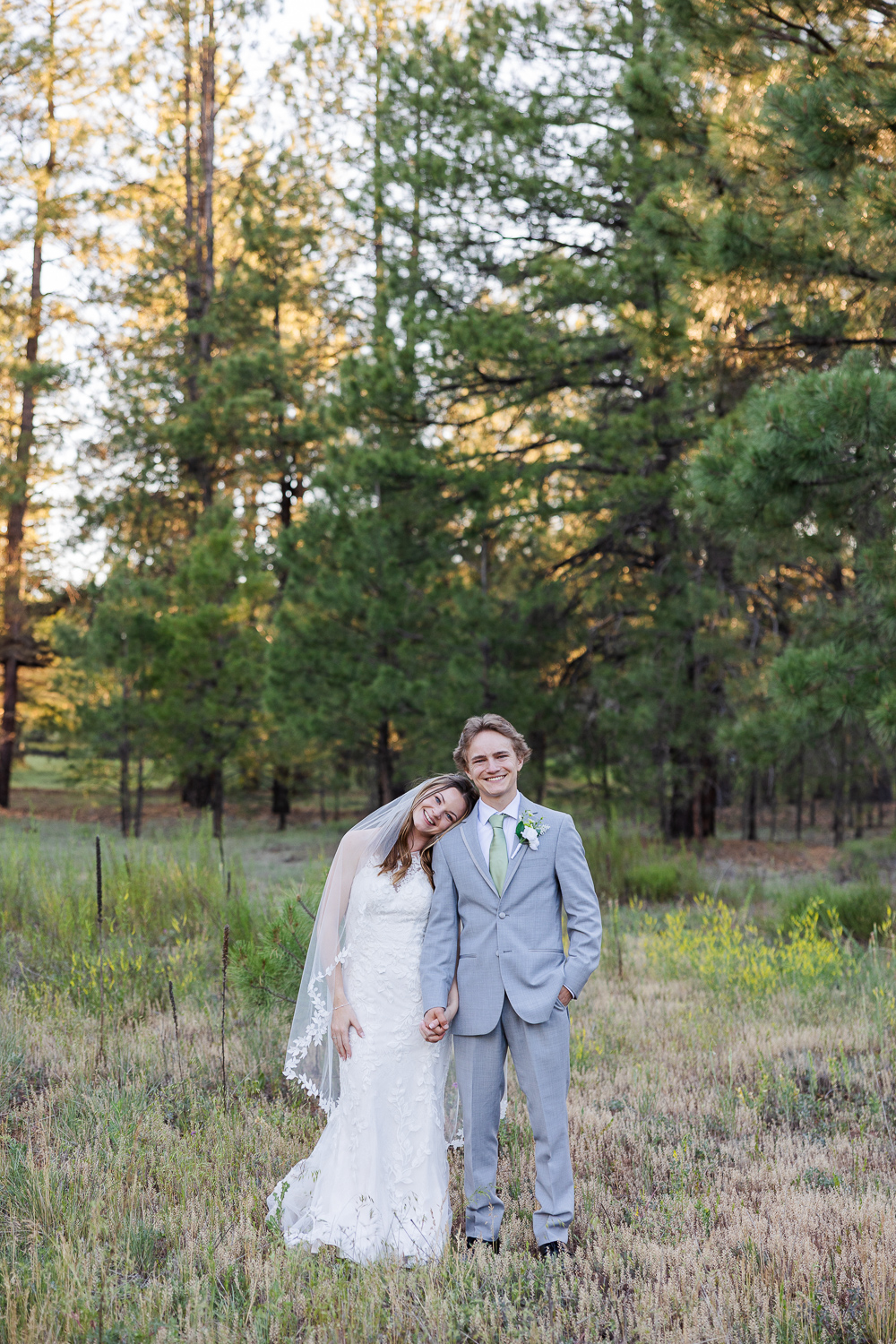 Bride and groom smiling at camera in the forest at Serendipity wedding venue in Flagstaff.