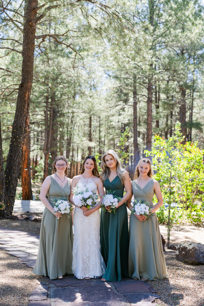 Bridesmaids smiling at camera in the forest at Serendipity Venue in Flagstaff. 