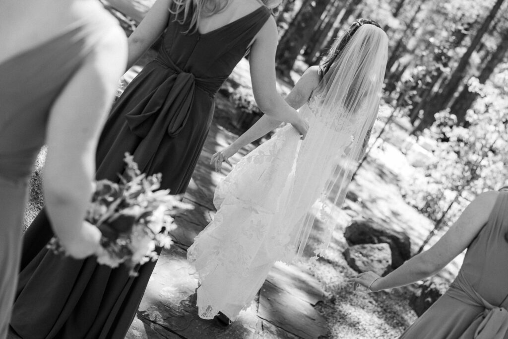 Bridesmaids holding bride's dress in the forest at Serendipity Venue in Flagstaff. 