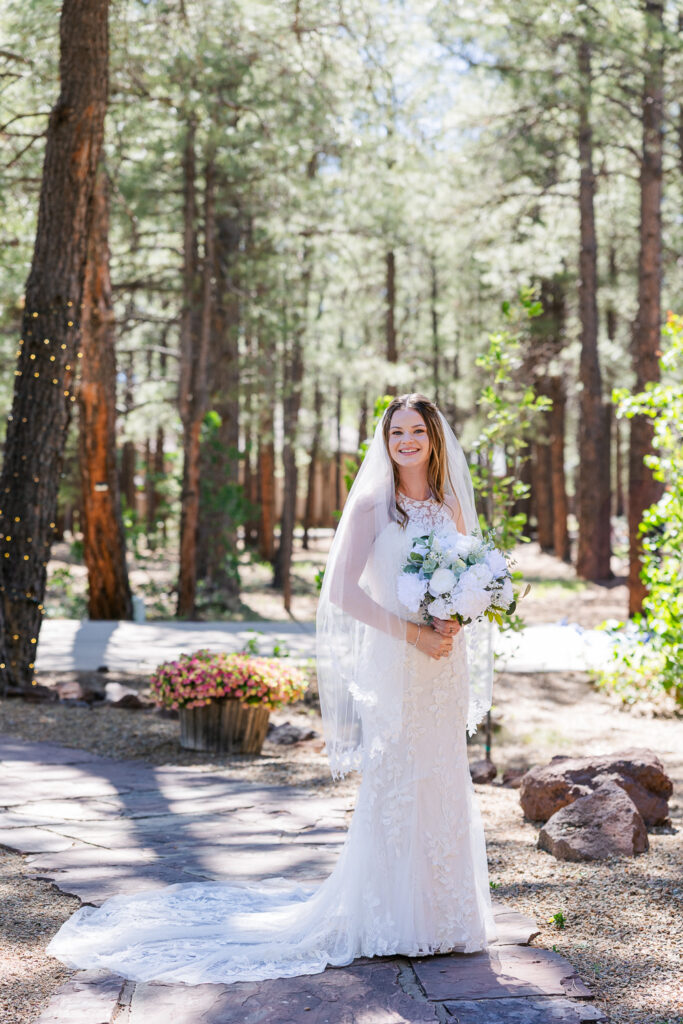 Bride smiling at camera in the forest at Serendipity Venue in Flagstaff.